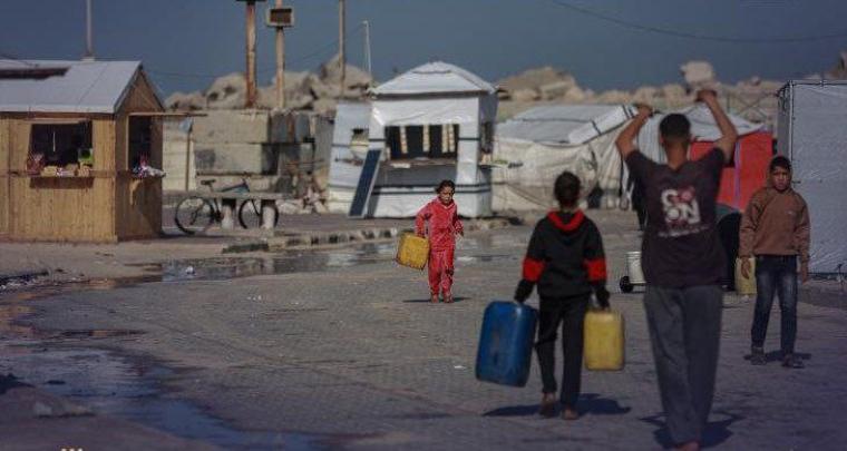 أطفال نازحون في غزة يحملون جالونات لتعبئة مياه الشرب