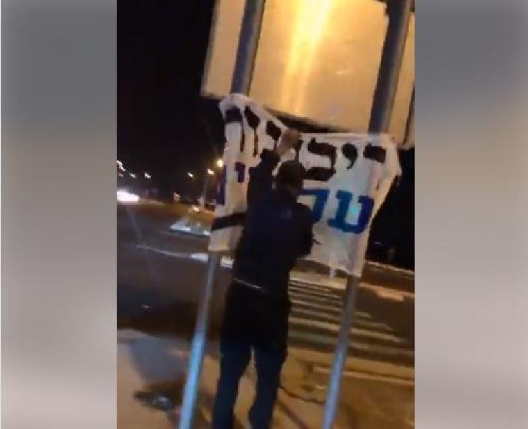 شاب فلسطيني يمزق يافطات اسرائيلية.JPG