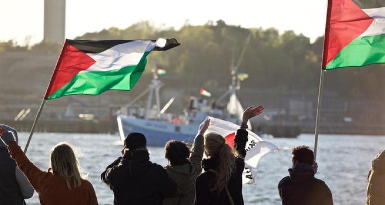فلسطينيون يلوحون لسفينة تركية 