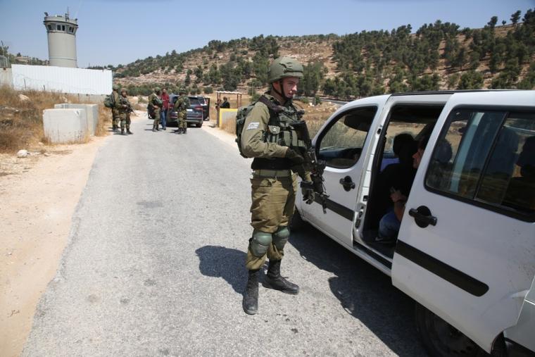 جندي من جيش الاحتلال الاسرائيلي يفتش مركبات المواطنين