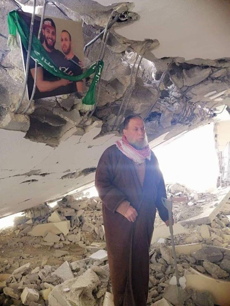 صورة والدة الشهيد صالح البرغوثي يقف على انقاض منزله المدمر