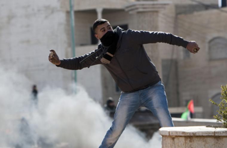 شاب يلقى الحجارة اتجاه قوات الاحتلال