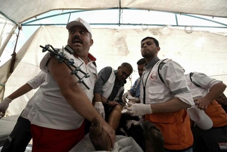 صورة للمسعف محمد الهسي خلال تقديم الاسعافات الاولية لمصاب في مسيرة العودة